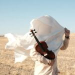 Man Wrapped White Fabric and Wearing in Beige Shirt Holding a Violin