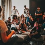 Group of multiethnic people gathering around female speaker in studio